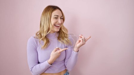 Photo for Young beautiful hispanic woman smiling pointing to the side over isolated pink background - Royalty Free Image