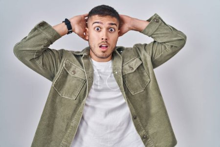 Photo for Young hispanic man standing over isolated background crazy and scared with hands on head, afraid and surprised of shock with open mouth - Royalty Free Image