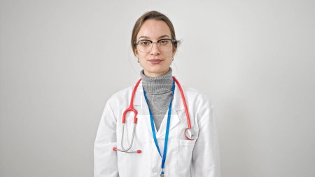 Foto de Mujer joven caucásica médico de pie con expresión seria sobre fondo blanco aislado - Imagen libre de derechos