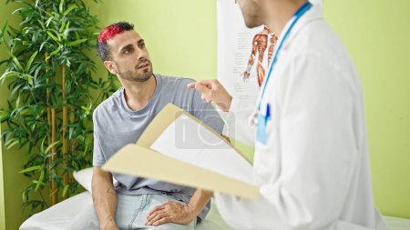 Foto de Dos hombres doctor y paciente teniendo consulta médica hablando en la clínica - Imagen libre de derechos