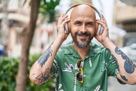 Photo for Young bald man smiling confident listening to music at street - Royalty Free Image
