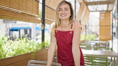 Photo for Young blonde woman waitress smiling confident standing at coffee shop terrace - Royalty Free Image