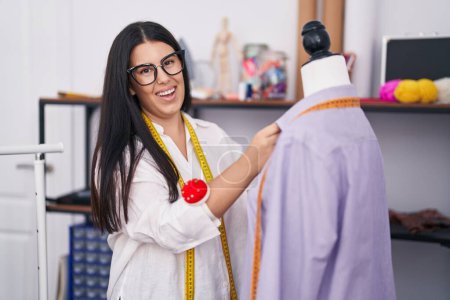Foto de Joven hermosa mujer hispana sastre sonriendo confiado medición camisa en atelier - Imagen libre de derechos