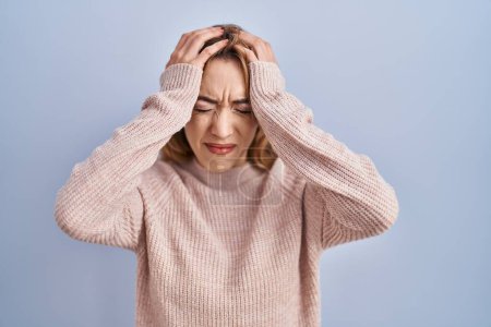Photo for Hispanic woman standing over blue background suffering from headache desperate and stressed because pain and migraine. hands on head. - Royalty Free Image