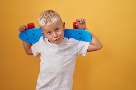 Photo for Little caucasian boy holding skate looking at the camera blowing a kiss being lovely and sexy. love expression. - Royalty Free Image