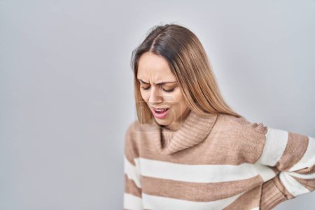 Photo for Young blonde woman wearing turtleneck sweater over isolated background suffering of backache, touching back with hand, muscular pain - Royalty Free Image