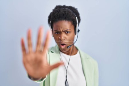 Photo for African american woman wearing call center agent headset doing stop gesture with hands palms, angry and frustration expression - Royalty Free Image