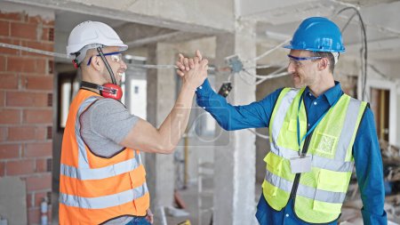 Photo for Two men builders shake hands speaking at construction site - Royalty Free Image