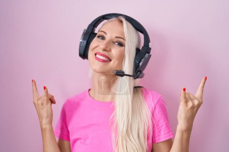 Photo for Caucasian woman listening to music using headphones shouting with crazy expression doing rock symbol with hands up. music star. heavy concept. - Royalty Free Image