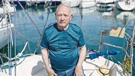 Téléchargez les photos : Homme âgé aux cheveux gris debout avec une expression détendue au bateau - en image libre de droit