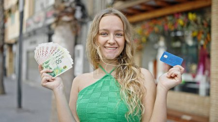 Foto de Joven mujer rubia con tarjeta de crédito y shekels israel en la calle - Imagen libre de derechos