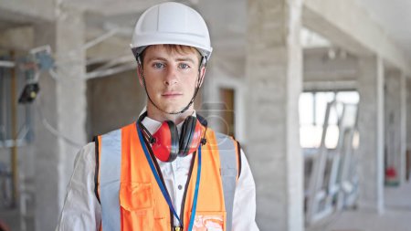 Téléchargez les photos : Jeune homme caucasien architecte debout avec une expression détendue sur le chantier de construction - en image libre de droit