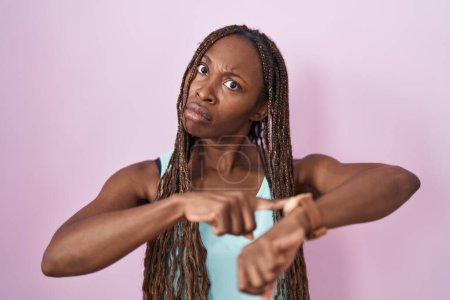 Photo for African american woman standing over pink background in hurry pointing to watch time, impatience, upset and angry for deadline delay - Royalty Free Image