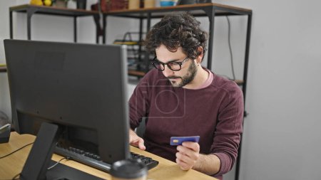Téléchargez les photos : Jeune homme hispanique travailleur d'affaires utilisant l'ordinateur et la carte de crédit de travail au bureau - en image libre de droit