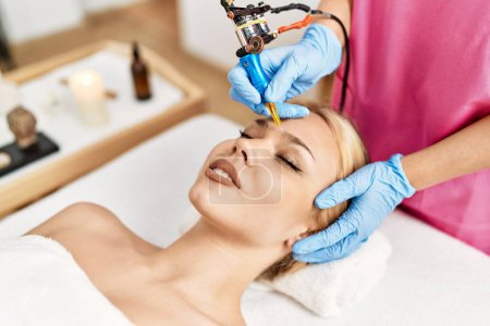 Young caucasian woman lying on table having microblading treatment at beauty salon