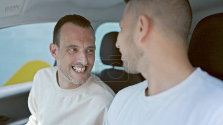 Téléchargez les photos : Deux hommes couple voiture de conduite parlant à la rue - en image libre de droit