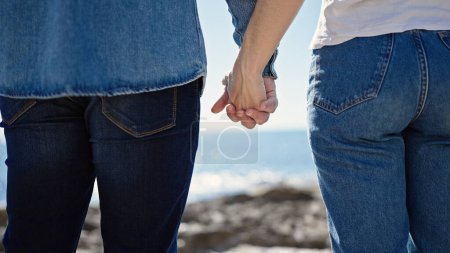 Foto de Hombre y mujer pareja de pie con las manos juntas al revés en la orilla del mar - Imagen libre de derechos