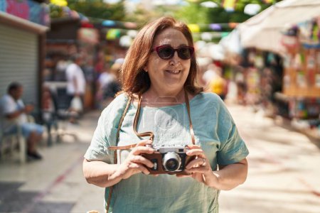 Photo for Senior woman tourist smiling confident holding camera at street - Royalty Free Image