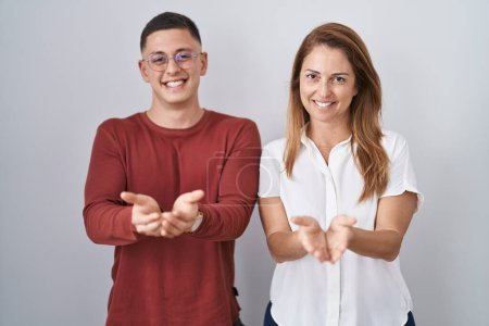 Photo for Mother and son standing together over isolated background smiling with hands palms together receiving or giving gesture. hold and protection - Royalty Free Image
