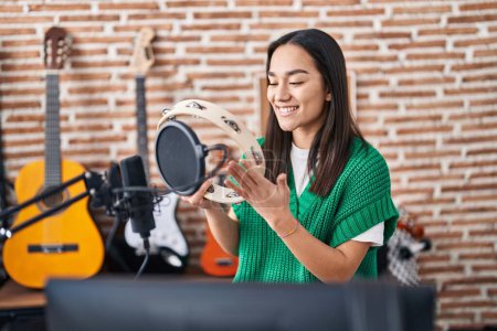 Foto de Joven músico hispano tocando pandereta en el estudio de música - Imagen libre de derechos