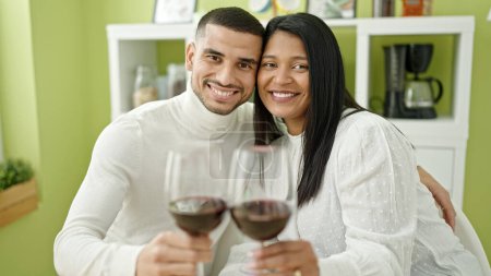 Photo for Man and woman couple hugging each other toasting with glass of wine at home - Royalty Free Image