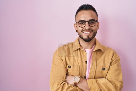 Téléchargez les photos : Jeune homme hispanique debout sur fond rose heureux visage souriant avec les bras croisés regardant la caméra. personne positive. - en image libre de droit
