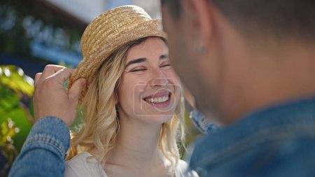 Téléchargez les photos : Homme et femme couple souriant confiant portant un chapeau d'été au parc - en image libre de droit