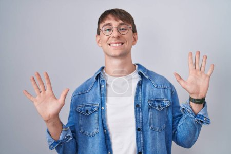 Photo for Caucasian blond man standing wearing glasses showing and pointing up with fingers number ten while smiling confident and happy. - Royalty Free Image