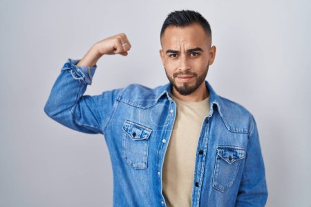 Téléchargez les photos : Jeune homme hispanique debout sur fond isolé personne forte montrant muscle du bras, confiant et fier de la puissance - en image libre de droit