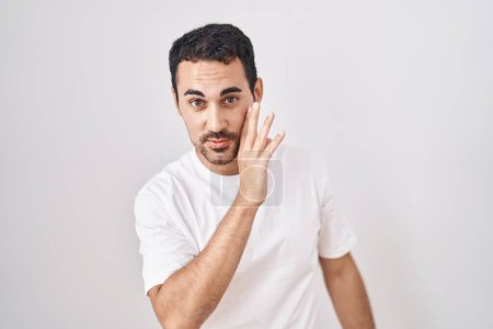 Photo for Handsome hispanic man standing over white background hand on mouth telling secret rumor, whispering malicious talk conversation - Royalty Free Image