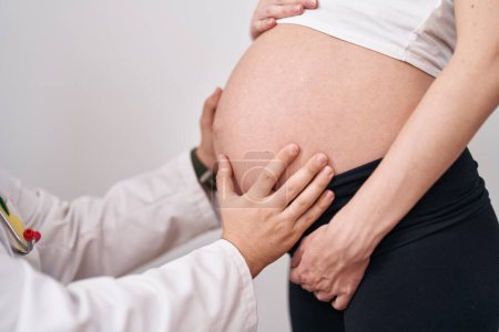 Foto de Hombre y mujer médico y paciente embarazada examinando vientre sobre fondo blanco aislado - Imagen libre de derechos