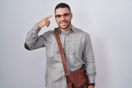 Photo for Young hispanic man wearing suitcase smiling pointing to head with one finger, great idea or thought, good memory - Royalty Free Image