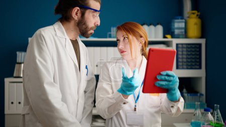 Téléchargez les photos : Homme et femme portant l'uniforme de scienciste utilisant le pavé tactile au laboratoire - en image libre de droit
