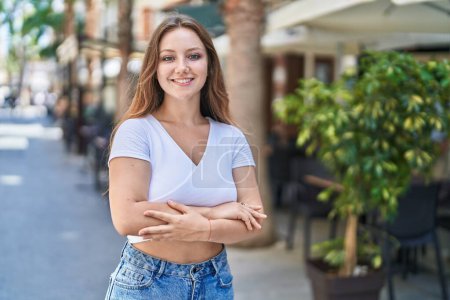 Photo for Young blonde woman standing with arms crossed gesture at street - Royalty Free Image