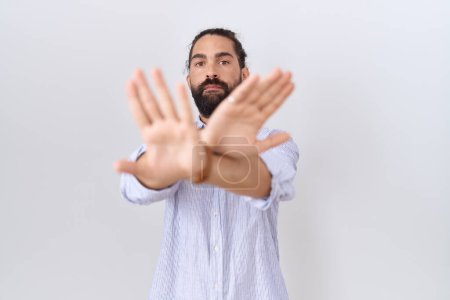 Foto de Hombre hispano con barba usando expresión casual de rechazo de camisa cruzando brazos y palmas haciendo signo negativo, cara enojada - Imagen libre de derechos