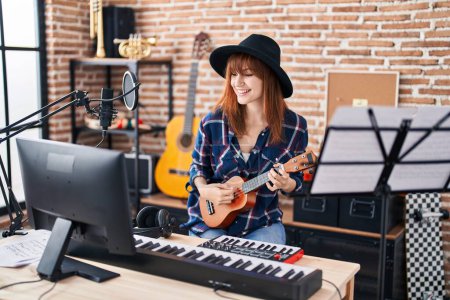Foto de Mujer joven músico cantando canción tocando ukelele en el estudio de música - Imagen libre de derechos