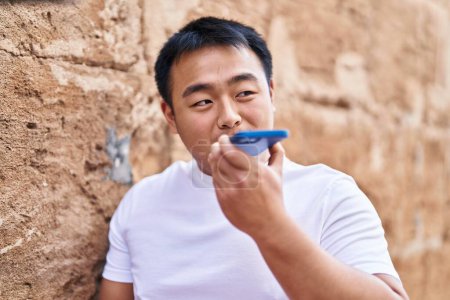 Téléchargez les photos : Young chinese man smiling confident talking on the smartphone at street - en image libre de droit