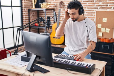 Téléchargez les photos : Jeune homme arabe musicien jouant du piano clavier au studio de musique - en image libre de droit