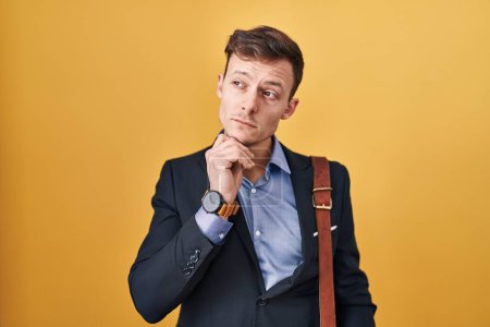 Photo for Caucasian business man over yellow background with hand on chin thinking about question, pensive expression. smiling with thoughtful face. doubt concept. - Royalty Free Image
