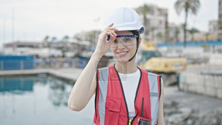 Téléchargez les photos : Jeune belle hispanique femme constructeur souriant confiance debout au bord de la mer - en image libre de droit