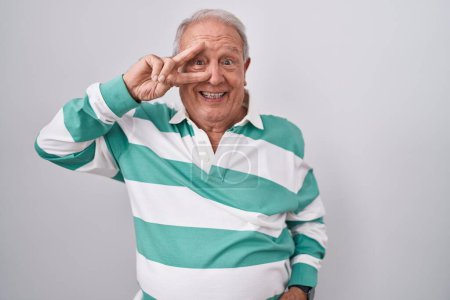 Photo for Senior man with grey hair standing over white background doing peace symbol with fingers over face, smiling cheerful showing victory - Royalty Free Image