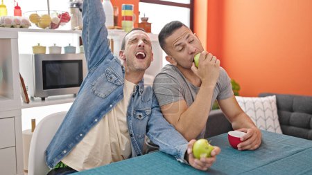 Foto de Dos hombres pareja comiendo manzana cantando canción en el comedor - Imagen libre de derechos
