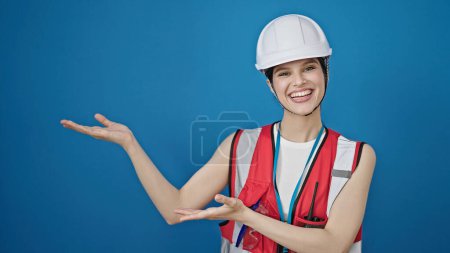 Photo for Young beautiful hispanic woman builder smiling confident presenting over isolated blue background - Royalty Free Image