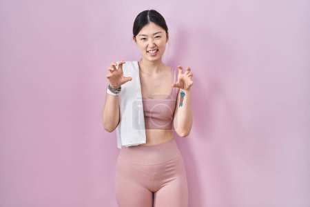 Photo for Chinese young woman wearing sportswear and towel smiling funny doing claw gesture as cat, aggressive and sexy expression - Royalty Free Image