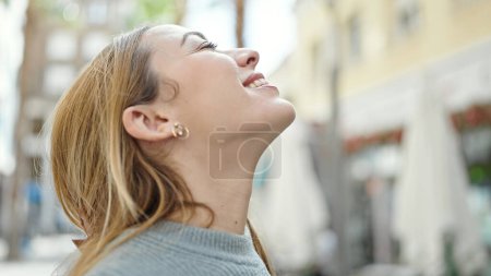 Téléchargez les photos : Jeune femme blonde respirant les yeux fermés sur la terrasse du café - en image libre de droit