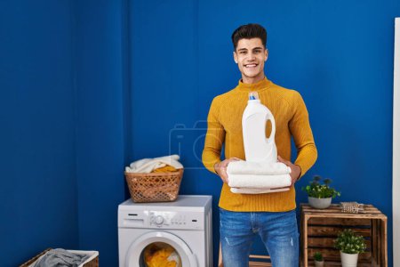 Photo for Young hispanic man holding clean towels smiling with a happy and cool smile on face. showing teeth. - Royalty Free Image