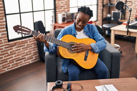 Foto de Músico afroamericano tocando guitarra clásica en estudio de música - Imagen libre de derechos