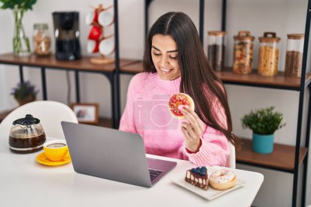 Photo for Young hispanic woman using laptop having breakfast at home - Royalty Free Image