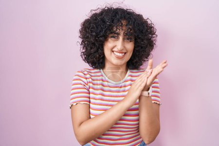 Téléchargez les photos : Jeune femme du Moyen-Orient debout sur fond rose applaudissements et applaudissements heureux et joyeux, souriant mains fiers ensemble - en image libre de droit