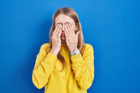 Photo for Young caucasian woman standing over blue background rubbing eyes for fatigue and headache, sleepy and tired expression. vision problem - Royalty Free Image